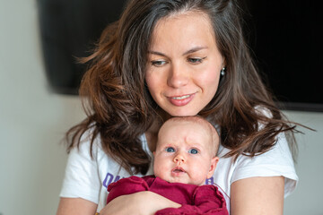 A newborn baby in the arms of his mother. Mother gently cuddles her baby