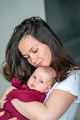 A newborn baby in the arms of his mother. Mother gently cuddles her baby