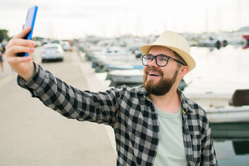 Traveller man taking selfie of luxury yachts marine during sunny day - travel and summer concept