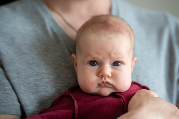 A serious newborn baby in his father's arms. Portrait of a newborn.