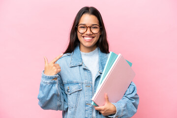 Young student Colombian woman isolated on pink background giving a thumbs up gesture
