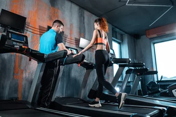  young beautiful woman has workout on treadmill with personal trainer and running © goami