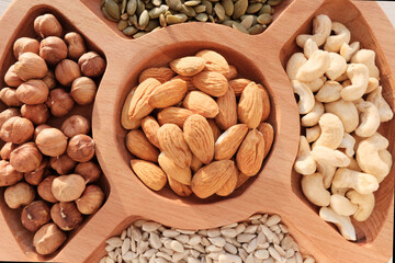 Mix of nuts, hazelnuts, cashews, seeds, peanuts. In a wooden plate, isolated object. The concept of healthy eating, vegetarianism.