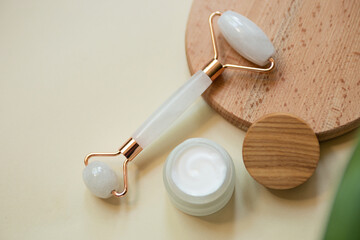 Top view of facial roller for massage on wooden slice.Pastel colors,eco friendly concept.