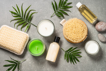 Fototapeta na wymiar Spa product composition with cosmetics, sea salt, towel and palm leaves at stone table. Flat lay image with copy space.