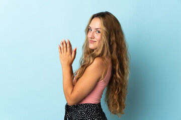 Young blonde woman isolated on blue background scheming something