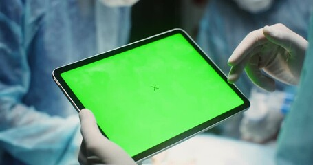 Close-up of a digital tablet with a green screen in the hands of a doctor