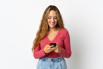 Young blonde woman isolated on blue background sending a message with the mobile