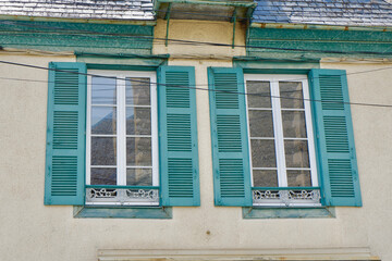 Charming vintage windows with colourful shutters on the retro house outside in Arreau town, France