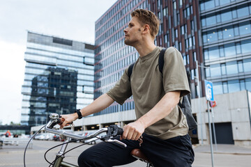 Young man riding a bike. Sustainable micro mobility transport New way of inclusive cities mobility. Green transportation. Sustainable climate neutral city goals. Green mobility and transportation - obrazy, fototapety, plakaty