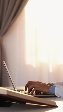 Vertical video. Medicine science. Smart man. Doctoral thesis. Unrecognizable male doctor typing laptop sitting desk with books light room interior.
