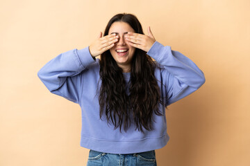 Young caucasian woman over isolated background covering eyes by hands and smiling