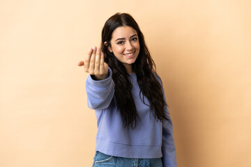 Young caucasian woman over isolated background inviting to come with hand. Happy that you came - obrazy, fototapety, plakaty