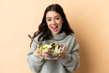 Young caucasian woman isolated on beige background holding a bowl of salad with happy expression