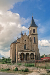Fototapeta premium Cloudy landscape with a stone church. Catholic church on the background of a cloudy sky.