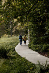 Fototapeta premium elderly couple holding hands walking the forest path in the national park in austria