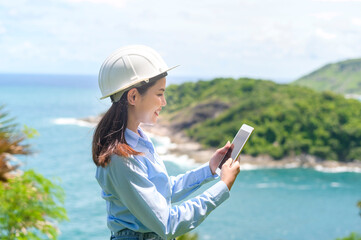 Female engineer working on the seaside wearing a protective helmet .