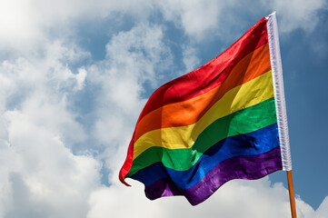 LGBTIQ flag with the colors of the rainbow on a blue sky with clouds