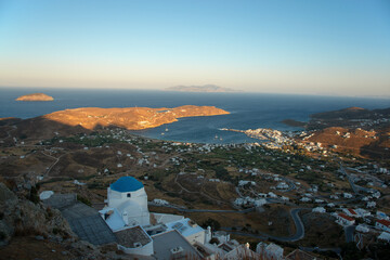Traditional style white church with blue dome on hill in Chora town and the view over the Livadi bay on Serifos island in Greece