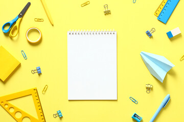 Blank paper notepad and school stationery on yellow table top view. Back to school concept