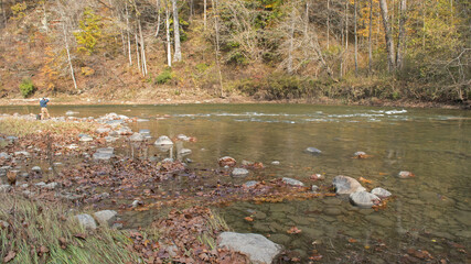 A man rests along Sugar Creek in Shades State Park, taking in the autumn season around him.