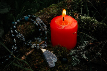burning candle, a symbol of the moon, an amulet lying on the moss on a dark natural background....