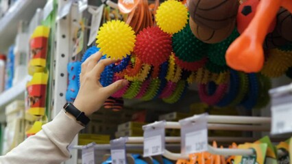 Close up of woman buying dog rubber toy in a pet store. Shopping and lifestyle concept
