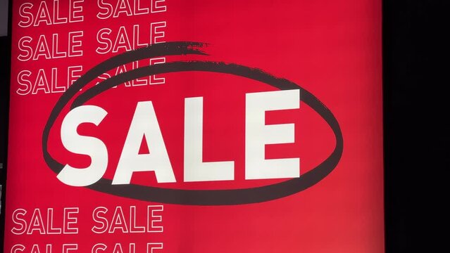 Sale banner is in the clothing shop window in shopping mall.