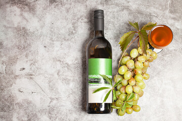 Obraz premium White wine bottle with bunch of grapes, glass on a dark background, top view.