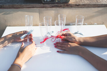 Beautiful female hands wine glasses. Wine glasses with red ribbons. Female hands with manicure.