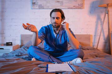 Sleepwalker in doctor uniform and stethoscope gesturing near clipboard on bed at night