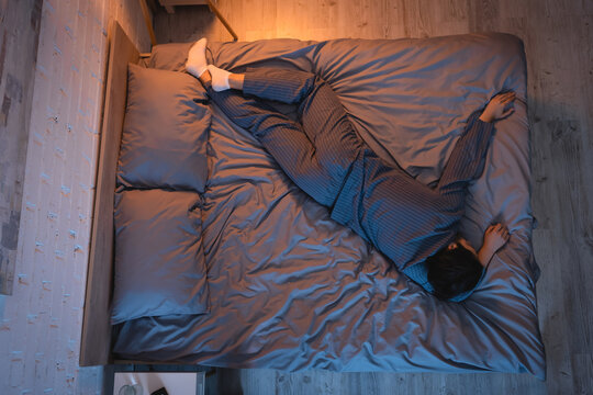 Side view of man in pajama and socks sleeping in bedroom