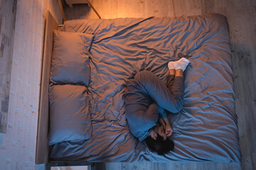 Side view of young man sleeping on bed at night