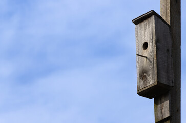 Old wooden birdhouse. Blue sky on the background.