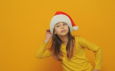 little girl in santa hat on yellow background with a copy space.