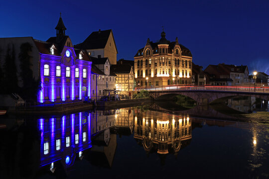 illuminated buildings and reflection on the river Werra in Eschwege by night