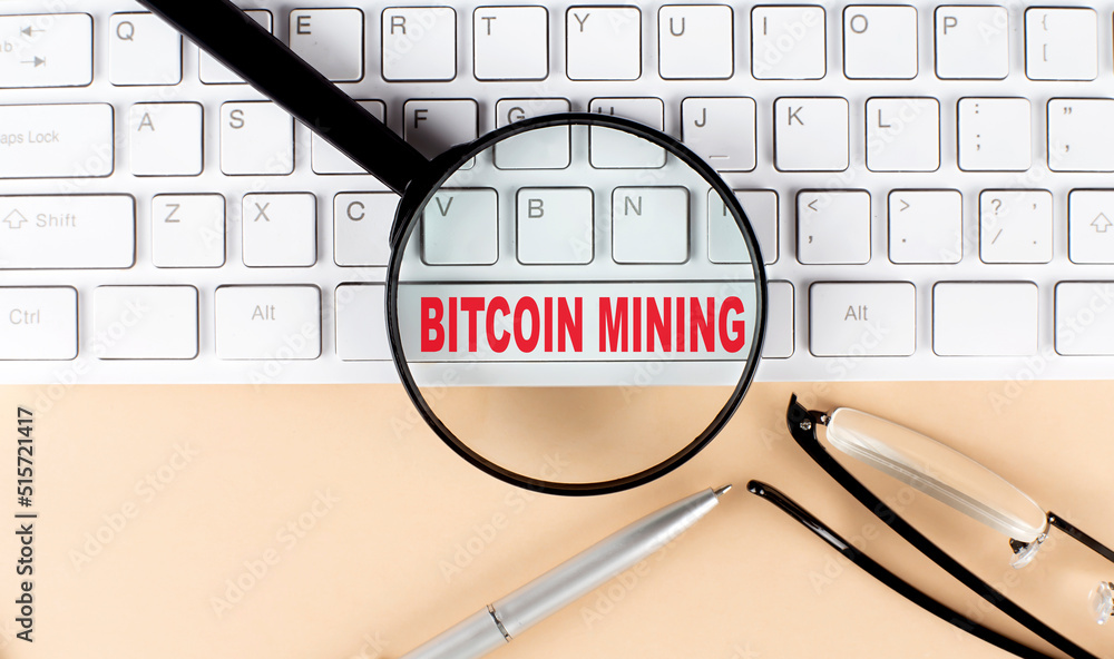 Aufkleber text bitcoin mining on keyboard with magnifier , glasses and pen on beige background