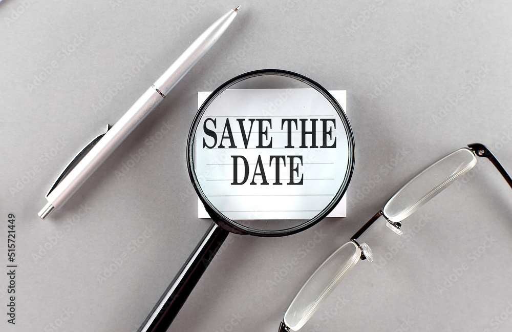Poster word save the date on sticky through magnifier on grey background