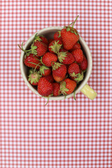 Cup of strawberries with a red gingham background