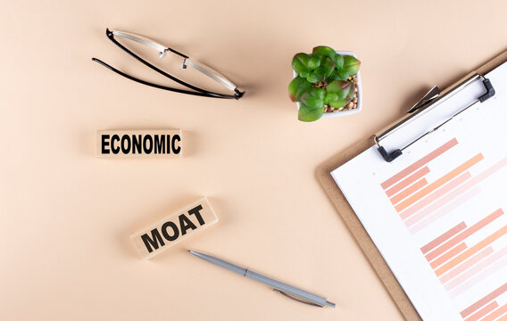 ECONOMIC MOAT Text On Wooden Block With Chart And Glasses, Business Concept