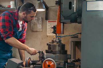 Young male mechanic with safety glasses on his head operating the machinery