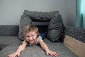 funny European child playing with pillows on couch