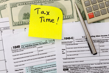 1040 US individual tax form, calculator, dollars, pen and yellow sticker