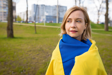 Outdoor portrait of a young woman with Ukrainian flag in the park. Free lifestyle