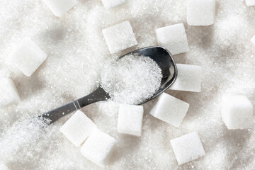 White sugar cubes and a teaspoon in granulated sugar. Refined cane sugar