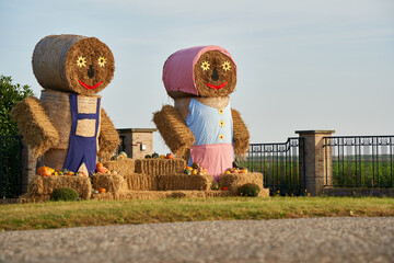 2 straw puppets on the wayside. Decorated with pumpkins. On Thanksgiving to halloween. Side view....
