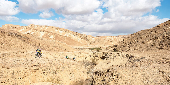 mountain cyclers on tandem bicycles near the ancient Nabatean Nekarot Fortress on the Spice Incense Route in the Negev in Israel under a partly cloudy sky