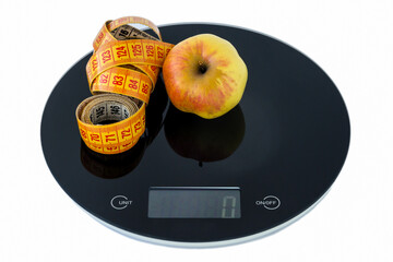 Apple and a measuring tape on the scales. Slimming concept. Isolated on a white background.