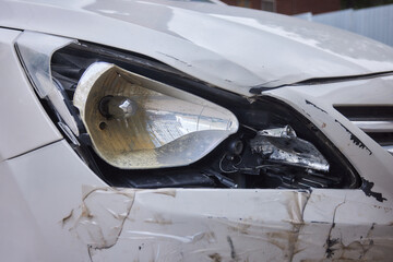 Damaged car broken headlights lens front bumper traffic accident.