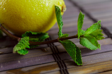 Lemon, leaves and sprigs of mint on a bamboo table